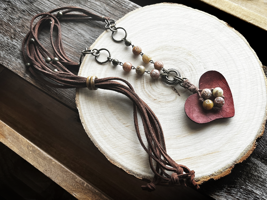 Boho chic earthy unique heart pendant long necklace on a rustic wooden board 