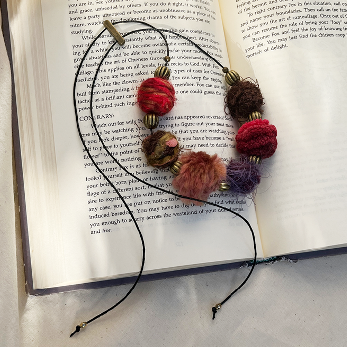 Shade of red yarn-wrapped necklace on a book